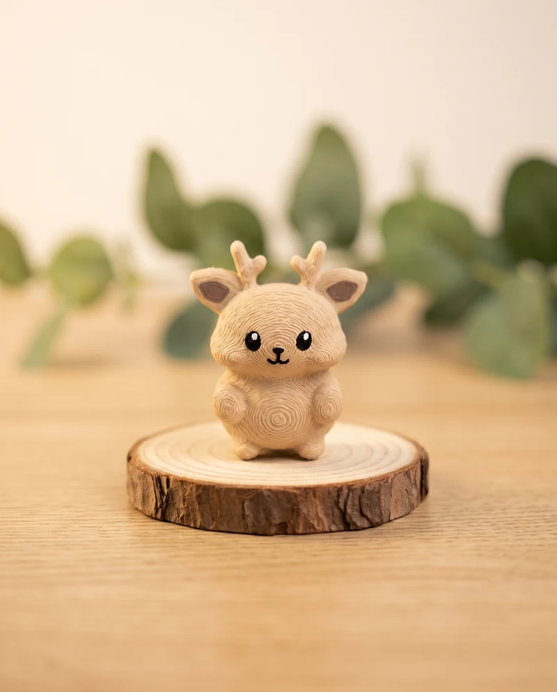 The printed Mofflits Deer, light tan with little antlers, standing on a wood slice