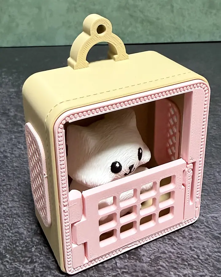 The blush carrier keychain from a three-quarter angle: cream body, blush-pink door, grate, and lattice side panel, with the Cat inside